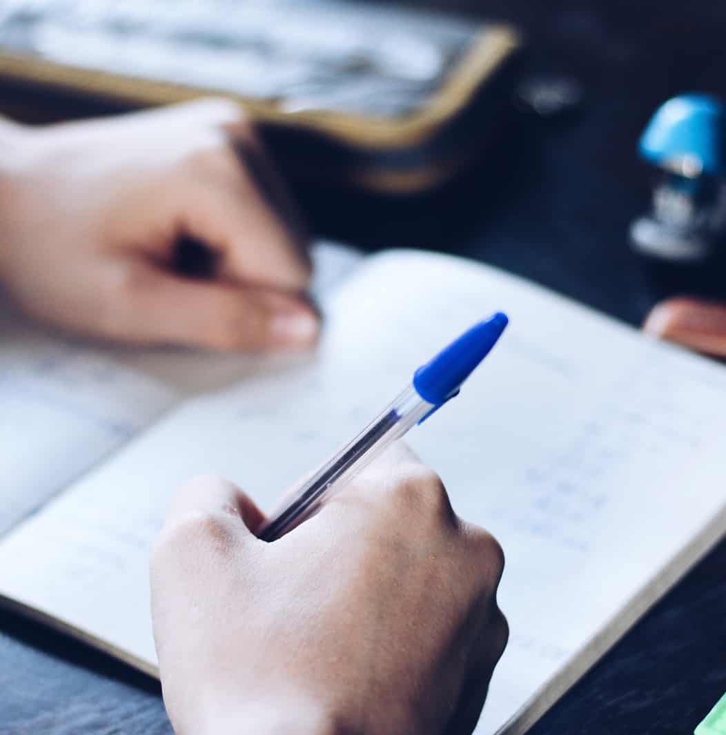 Writing in a notebook with a blue ballpoint pen